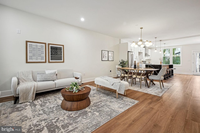 living area featuring a chandelier, recessed lighting, baseboards, and wood finished floors