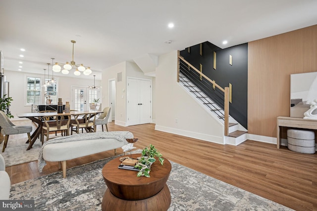 living area featuring light wood finished floors, baseboards, stairway, and a chandelier