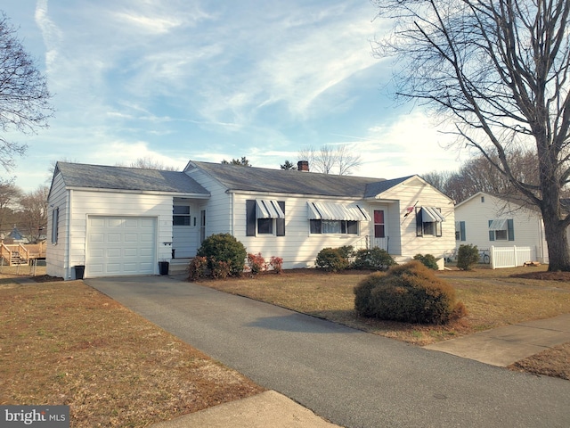 single story home featuring driveway, a chimney, an attached garage, and a front yard