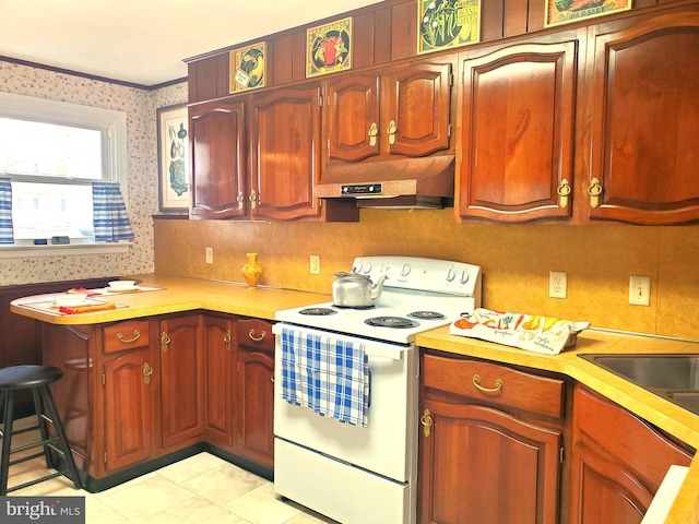 kitchen with white electric stove, light countertops, wallpapered walls, and under cabinet range hood