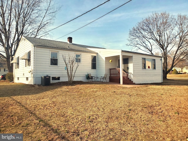 back of house featuring central air condition unit, a chimney, and a yard