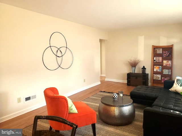 living area featuring visible vents, baseboards, and wood finished floors