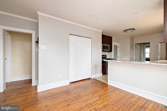 unfurnished living room featuring crown molding, light wood-style flooring, and baseboards