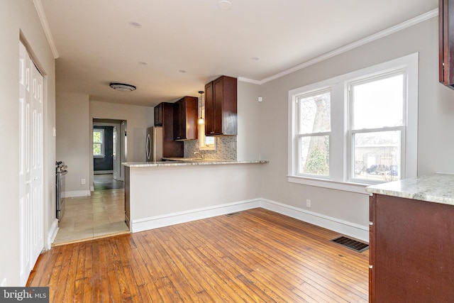 kitchen with visible vents, decorative backsplash, ornamental molding, light wood-type flooring, and plenty of natural light