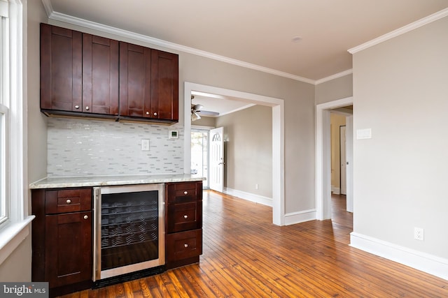 kitchen with wine cooler, dark wood finished floors, backsplash, ornamental molding, and baseboards