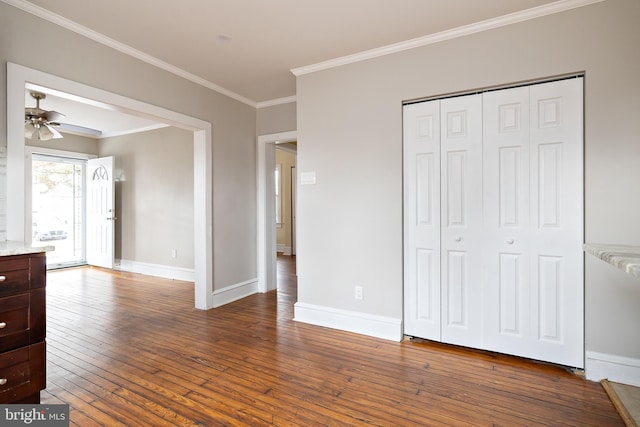 unfurnished bedroom with wood-type flooring, a closet, baseboards, and crown molding