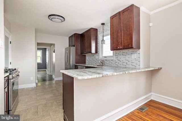 kitchen with stainless steel appliances, decorative backsplash, a sink, a peninsula, and baseboards