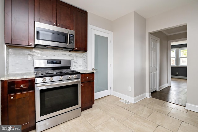 kitchen with light stone countertops, tasteful backsplash, appliances with stainless steel finishes, and baseboards