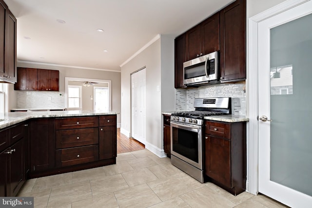 kitchen with dark brown cabinetry, appliances with stainless steel finishes, light stone counters, and ornamental molding