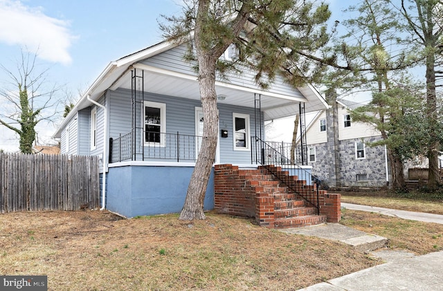 bungalow-style house with covered porch, stairs, and fence