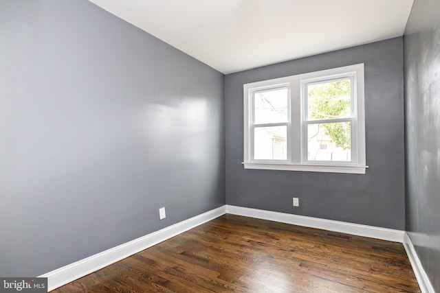 empty room featuring dark wood-style flooring and baseboards