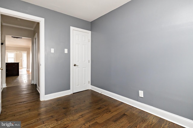 unfurnished bedroom featuring dark wood-style floors, ornamental molding, and baseboards