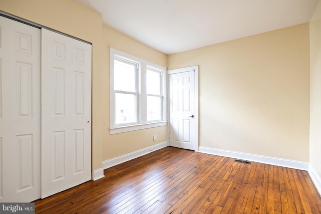 unfurnished bedroom featuring visible vents, dark wood finished floors, and baseboards