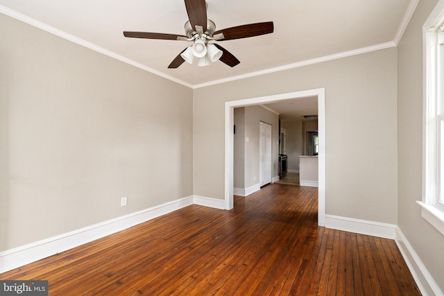 empty room featuring ornamental molding, a ceiling fan, hardwood / wood-style flooring, and baseboards