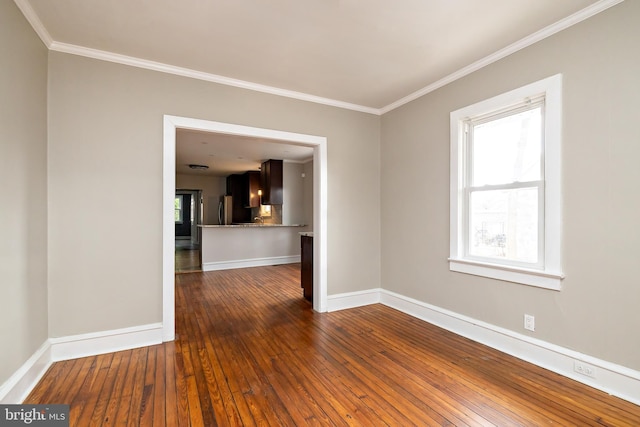 unfurnished room featuring crown molding, wood-type flooring, and baseboards