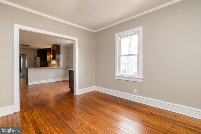 empty room with baseboards, ornamental molding, and hardwood / wood-style floors