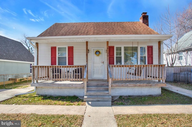 bungalow-style house with a porch, roof with shingles, and a chimney