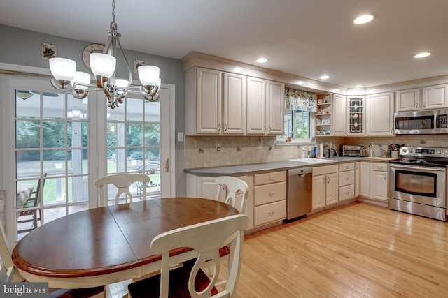 kitchen with recessed lighting, light wood-style floors, hanging light fixtures, appliances with stainless steel finishes, and decorative backsplash