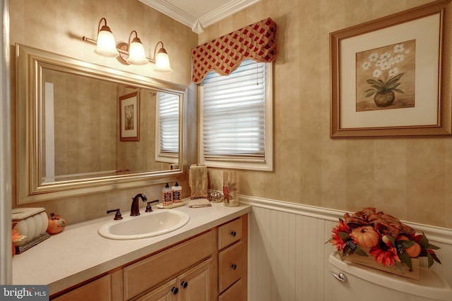 half bathroom featuring toilet, wainscoting, vanity, and crown molding