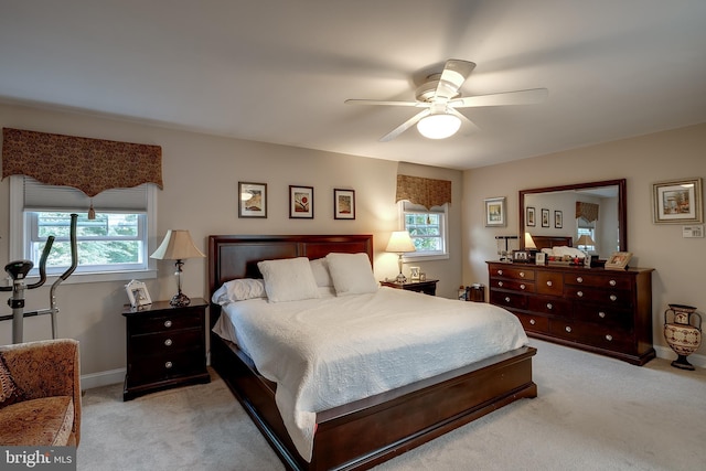 bedroom featuring light carpet, multiple windows, and a ceiling fan