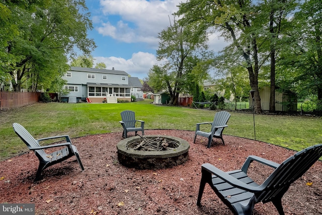 view of yard with a storage shed, an outdoor fire pit, a sunroom, a fenced backyard, and an outdoor structure