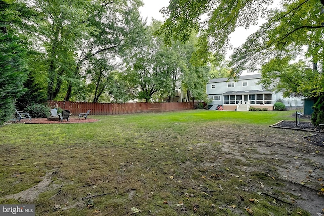 view of yard featuring an outdoor fire pit, fence, and a sunroom