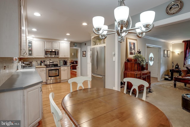 dining area with a toaster, crown molding, light wood-type flooring, a notable chandelier, and recessed lighting