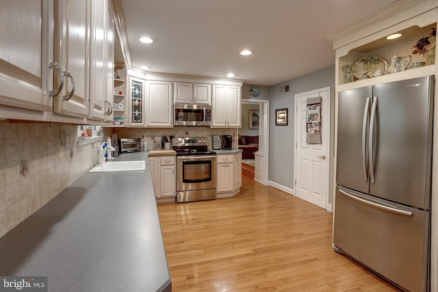 kitchen with stainless steel appliances, light wood-type flooring, a sink, and open shelves