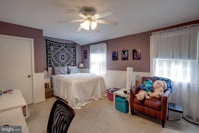 bedroom with lofted ceiling, carpet, a ceiling fan, and wainscoting