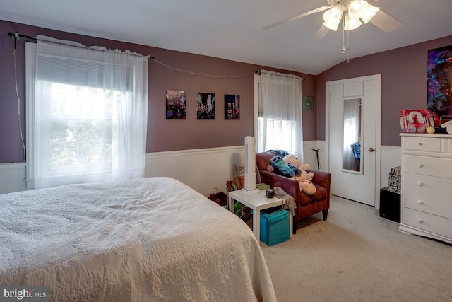 bedroom with carpet, multiple windows, wainscoting, and lofted ceiling