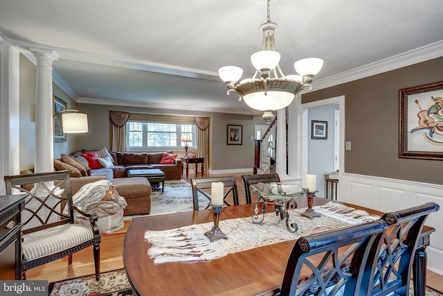 dining space featuring ornamental molding, stairway, wood finished floors, and ornate columns