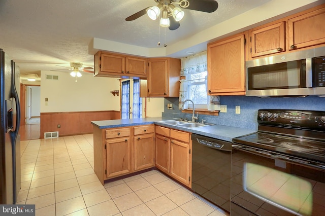 kitchen featuring a wainscoted wall, visible vents, a sink, a textured ceiling, and black appliances