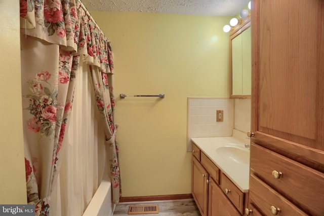 bathroom featuring visible vents, decorative backsplash, vanity, a textured ceiling, and baseboards