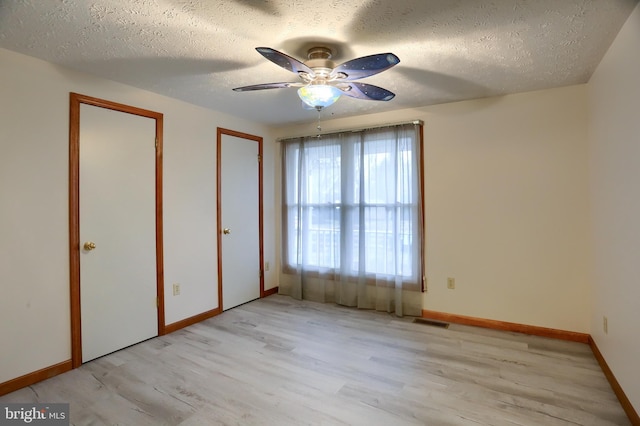 unfurnished bedroom with baseboards, a textured ceiling, visible vents, and wood finished floors