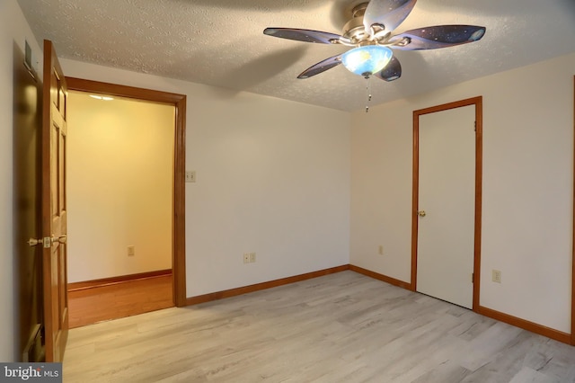 empty room with a textured ceiling, ceiling fan, baseboards, and light wood-style floors