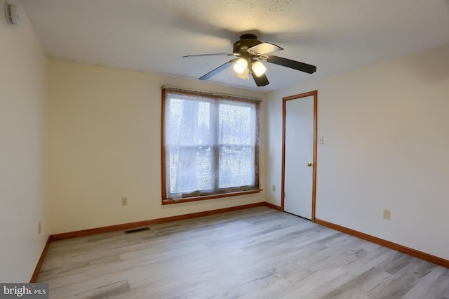 empty room with light wood-type flooring, baseboards, visible vents, and a ceiling fan