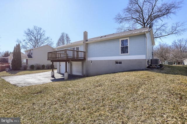 rear view of property with metal roof, a garage, central AC, driveway, and a lawn