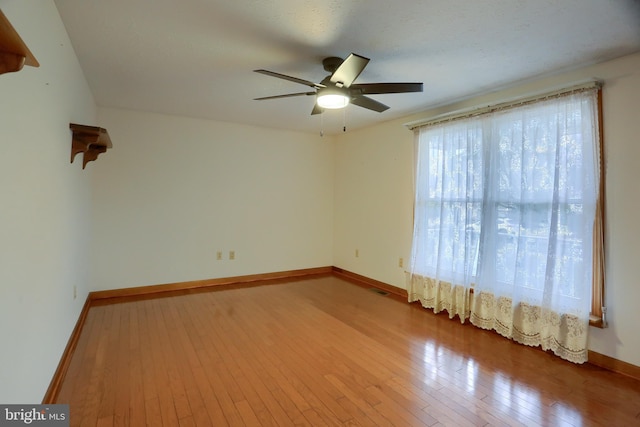 empty room with wood-type flooring, visible vents, baseboards, and ceiling fan