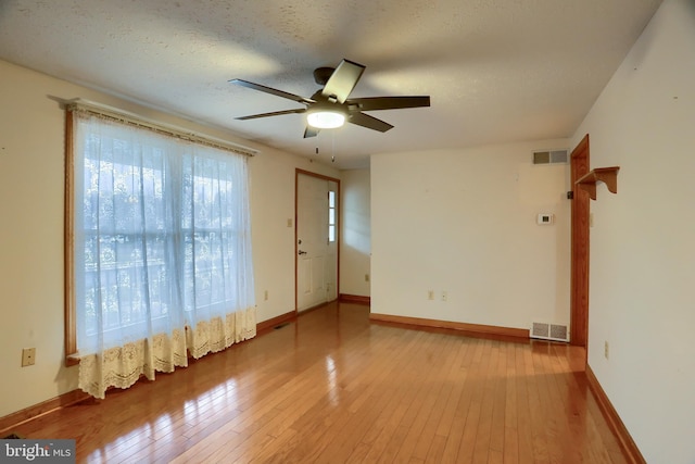 spare room with a textured ceiling, hardwood / wood-style floors, visible vents, and baseboards