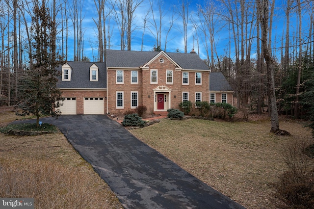 view of front of house featuring a garage, aphalt driveway, roof with shingles, a front lawn, and brick siding