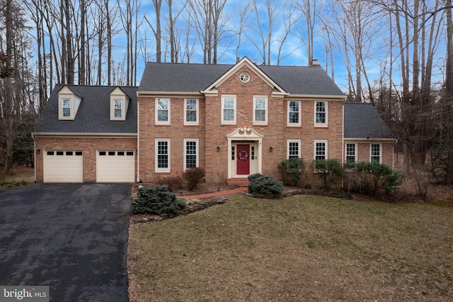 view of front of property with a garage, a front yard, aphalt driveway, and brick siding