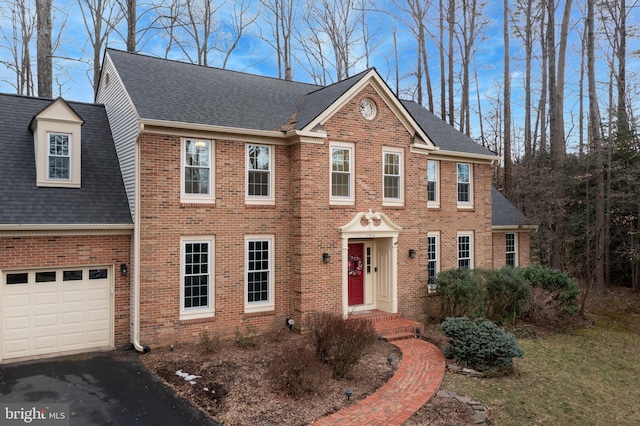 view of front of home featuring a garage, roof with shingles, aphalt driveway, and brick siding