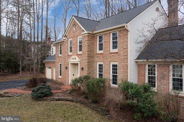 view of front of property with brick siding, roof with shingles, and aphalt driveway