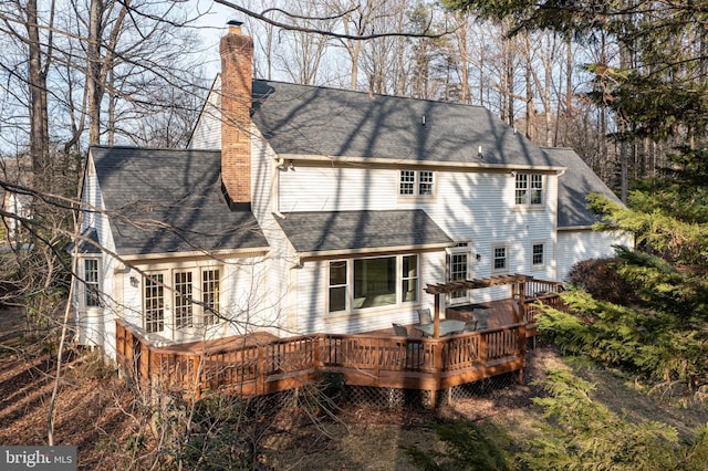 back of property with roof with shingles, a chimney, and a wooden deck