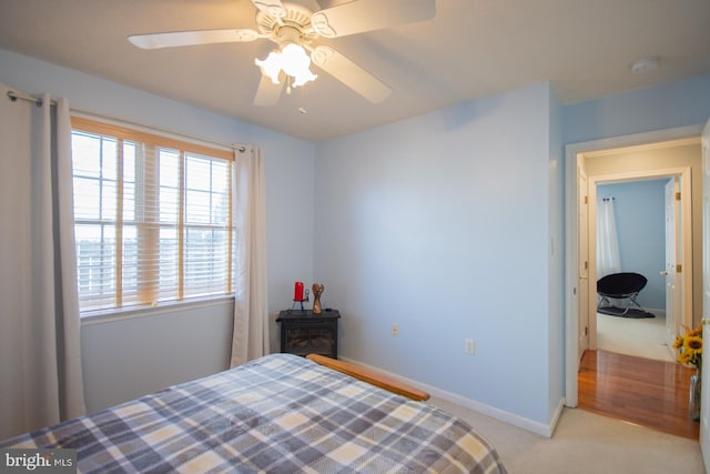 bedroom with light carpet, a ceiling fan, and baseboards