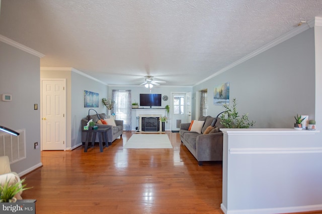 living room with a textured ceiling, a fireplace, a ceiling fan, and wood finished floors