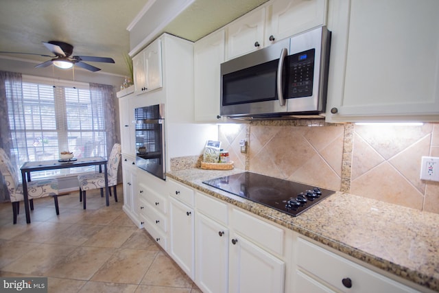 kitchen featuring stainless steel appliances, light stone countertops, white cabinetry, and decorative backsplash