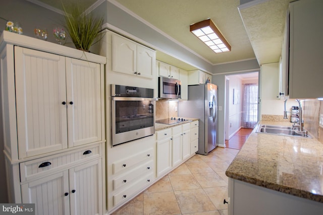 kitchen featuring light tile patterned floors, white cabinets, stainless steel appliances, crown molding, and a sink