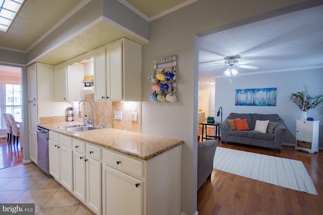 kitchen featuring stainless steel dishwasher, crown molding, light stone counters, and a sink