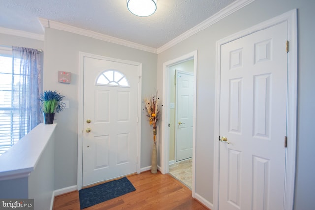 foyer with ornamental molding, a textured ceiling, baseboards, and wood finished floors